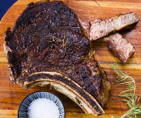 rib eye steak on the wooden board salt pepper and rosemary